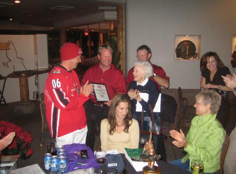 Jeff Burghardt of Prince Rupert Grain makes Ted an honorary Canadian with gifts of a tuque, Winnipeg Jets jersey and fresh-brewed Canadian water. The Canadians were the stars the day before the tourney when they poured out of their SUV's on Scottsdale's Thompson Peak Parkway --- dressed in their golf clothes --- and helped tired workers hammer billboard signs into the hard caliche for the tournament. Arlene Purdy, Nadine Huiskamp and Jo-em Purdy cheer.