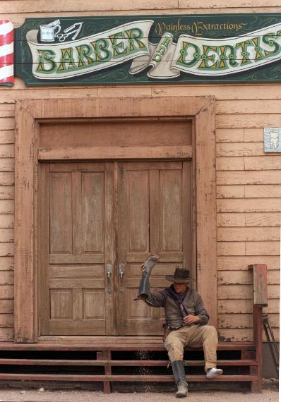 Reporter Jim Purdy takes a much-needed break from playing cowboy to empty the uncomfortable gravel from his boots. This, as Purdy has learned, is one of the hazards of working as a stuntman for a day at Old Tucson Studios.